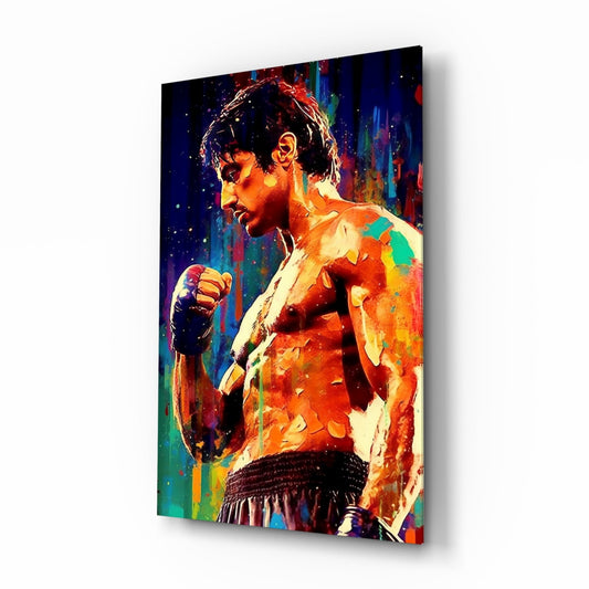 Angled side view of a glass wall art panel displaying a shirtless boxer in profile with vibrant rainbow colors and paint splatters on a dark background.