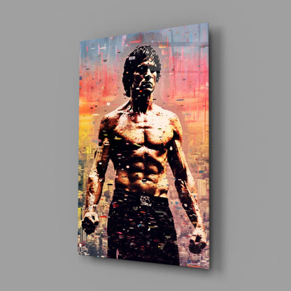 Angled view of glass wall art featuring a shirtless muscular man superimposed over a sunset cityscape with warm orange and yellow tones.