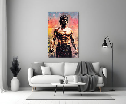 Colorful glass wall art depicting a shirtless muscular man against a pixelated cityscape in warm sunset tones, displayed above a white sofa in a modern living room.