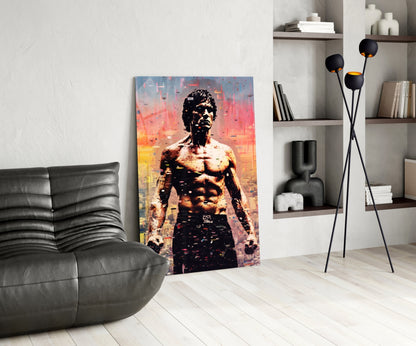 Modern living room with glass wall art depicting a shirtless man against an orange and blue cityscape backdrop, displayed beside a black leather chair and floor lamp.