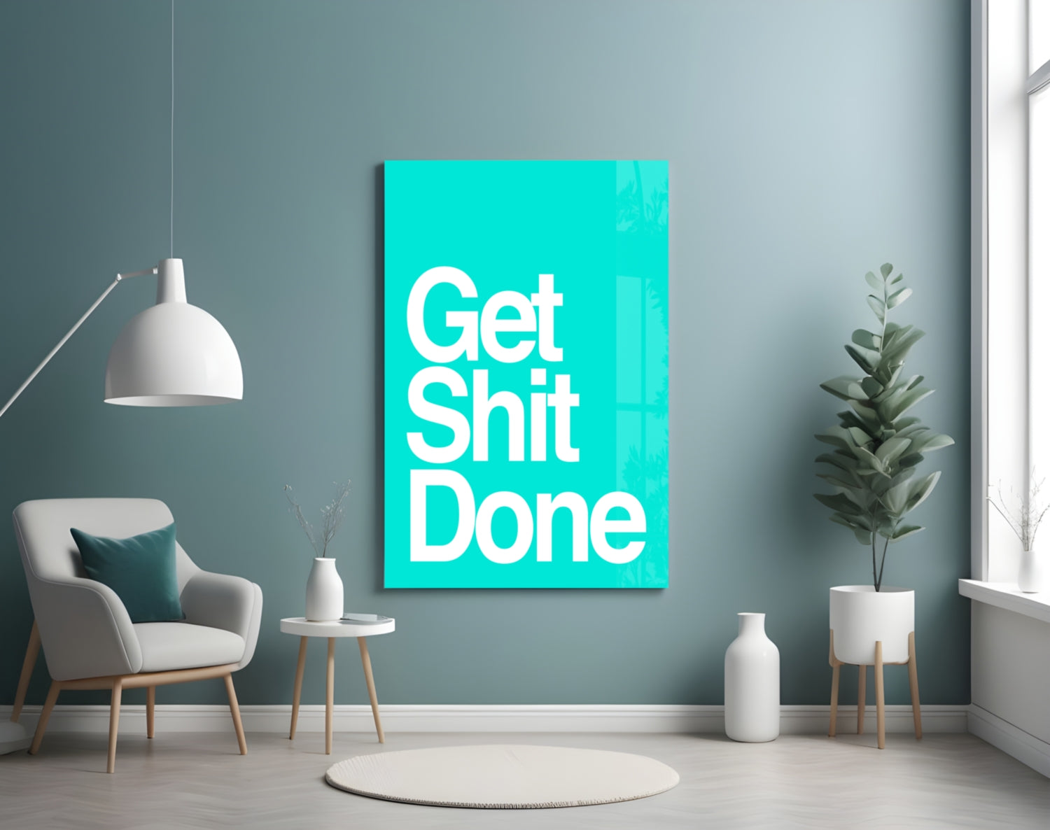 Bright turquoise glass wall art displaying "Get Shit Done" in white text, mounted in a modern living room setting with gray walls, furniture, and potted plants.