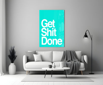 Turquoise glass wall art displaying "Get Shit Done" in white text, mounted above a white sofa in a modern living room.