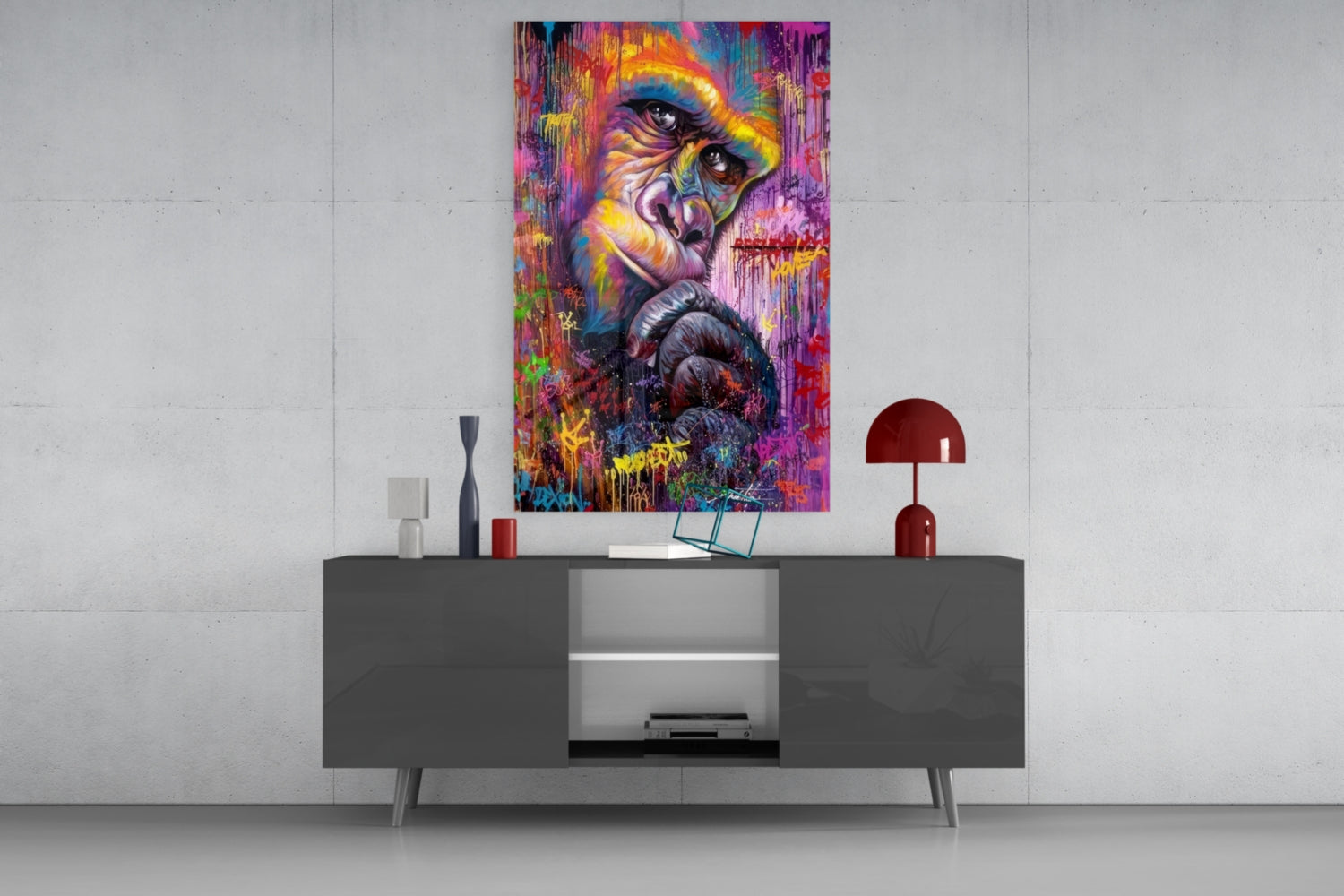 Colorful abstract primate portrait glass art hanging above modern gray console table with red lamp and decorative accessories.