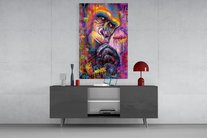 Colorful abstract primate portrait glass art hanging above modern gray console table with red lamp and decorative accessories.