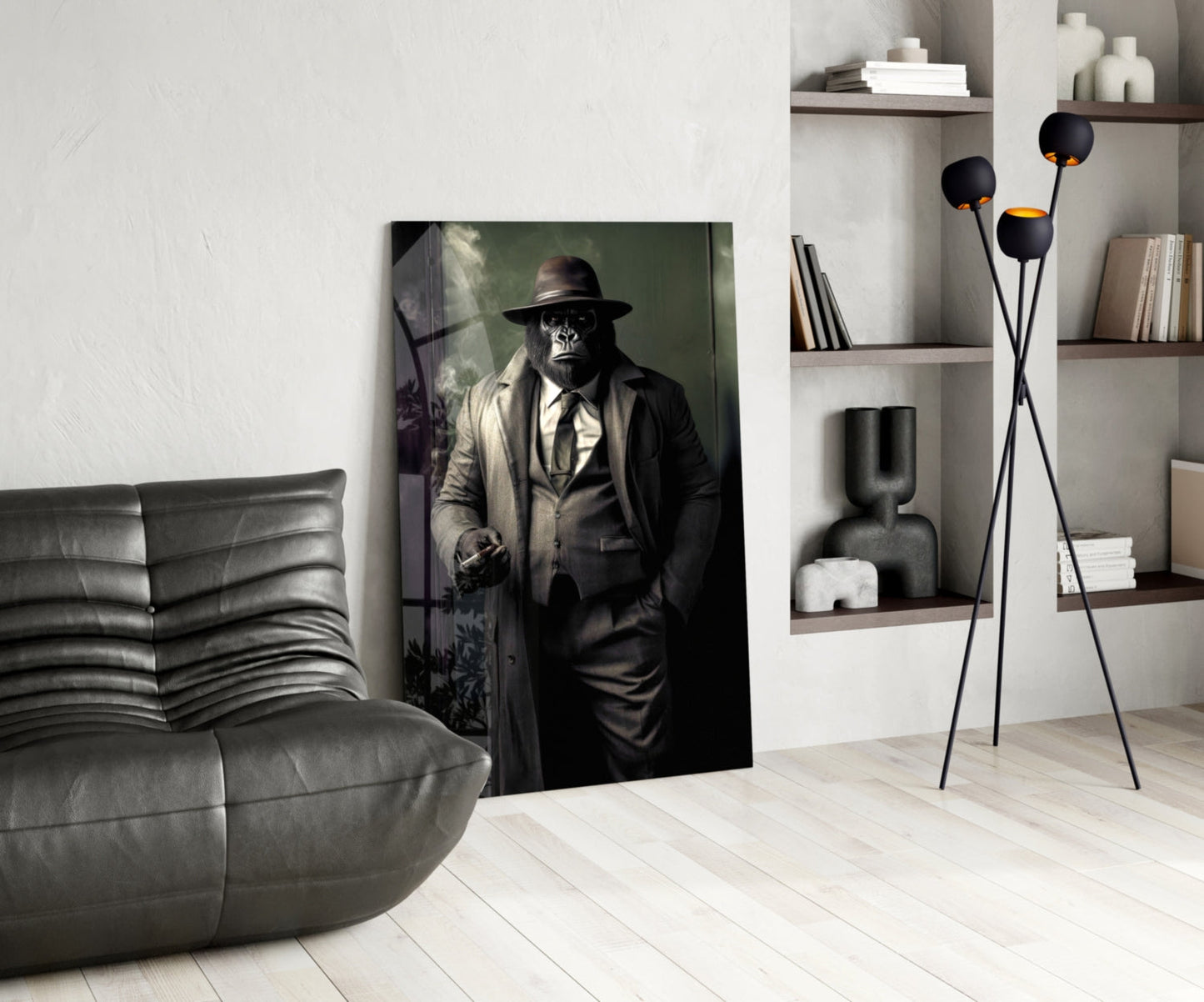 Modern living room interior featuring a glass wall art print of a chimpanzee in formal business attire and fedora hat, displayed leaning against white wall beside gray leather chair.