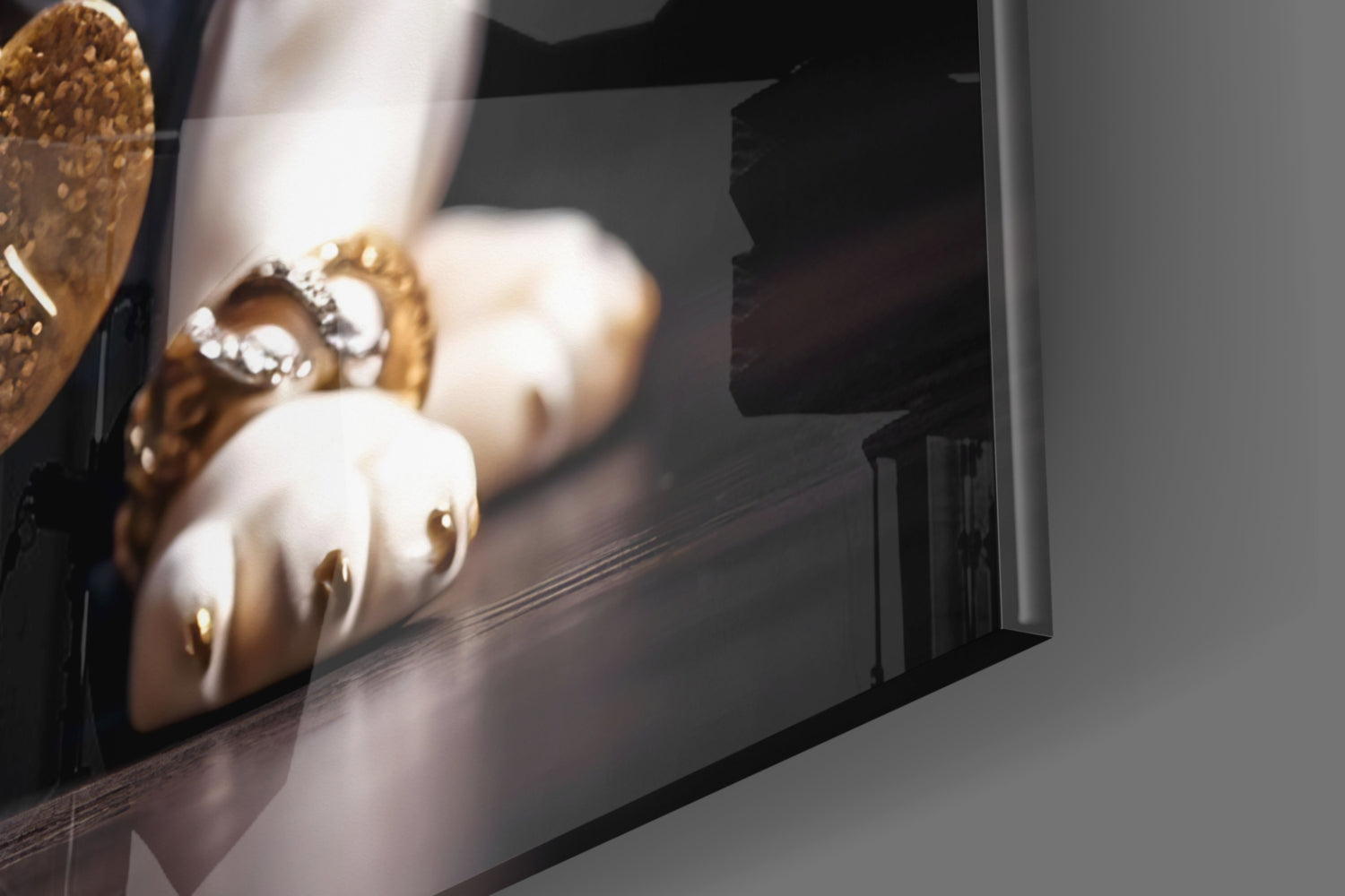 Close-up angled view of glass wall art displaying cream and gold decorative puppy figurines with rhinestone embellishments on dark surface.