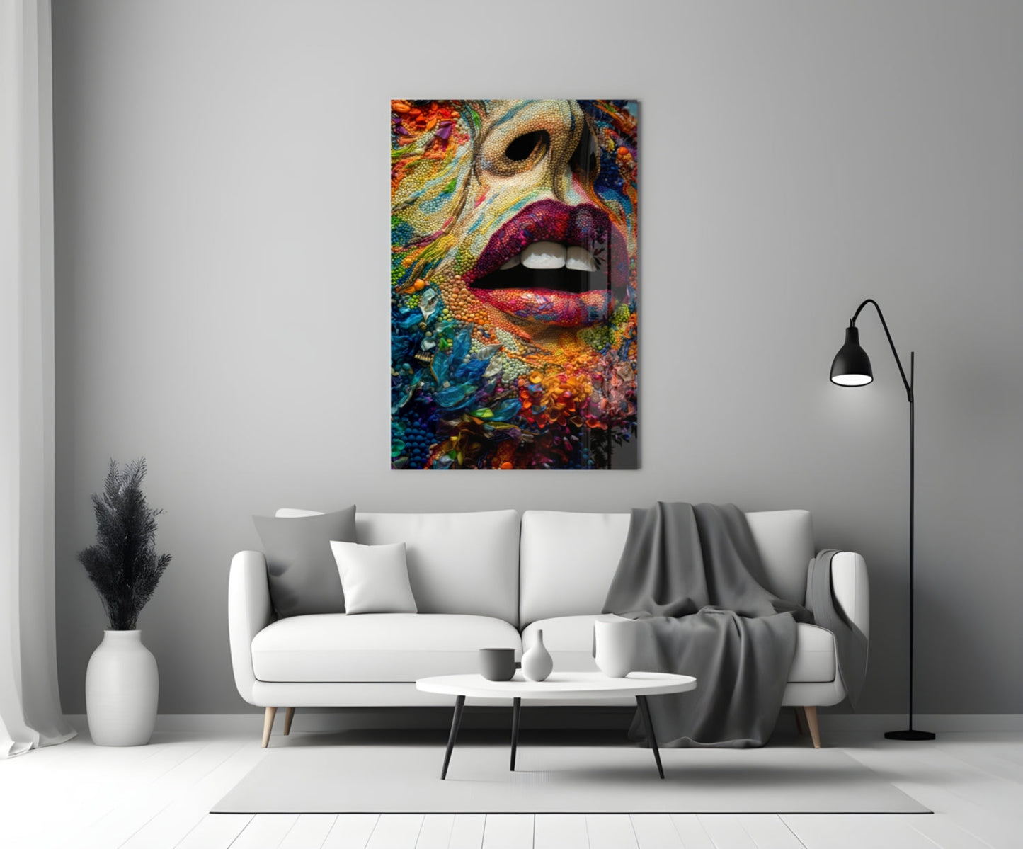 Colorful glass wall art depicting a woman's face with vibrant multicolored patterns and bold pink lips, displayed above a white sofa in a minimalist interior setting.