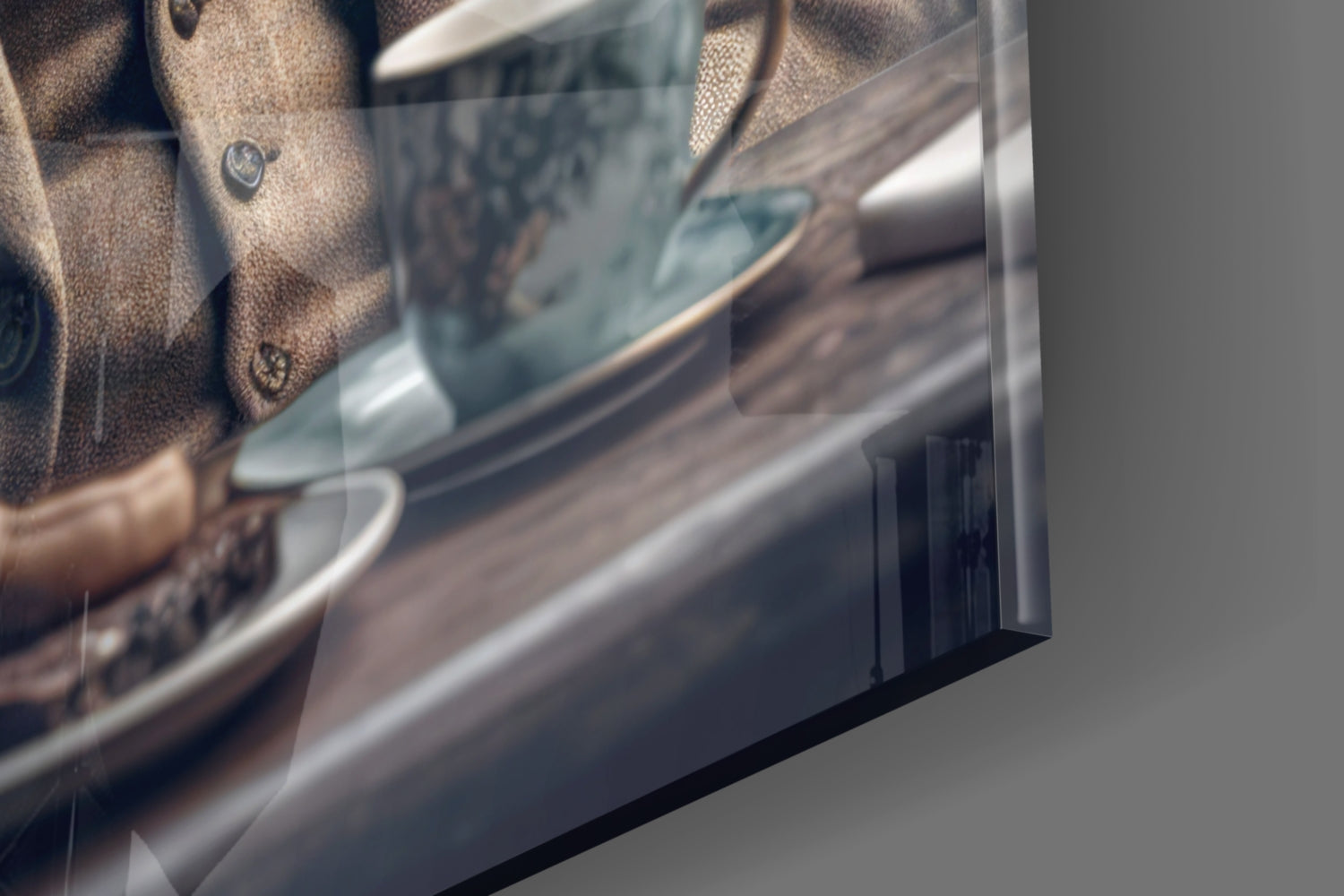 Close-up angled view of glass art print edge showing beige textured fabric and blue tones against gray background.