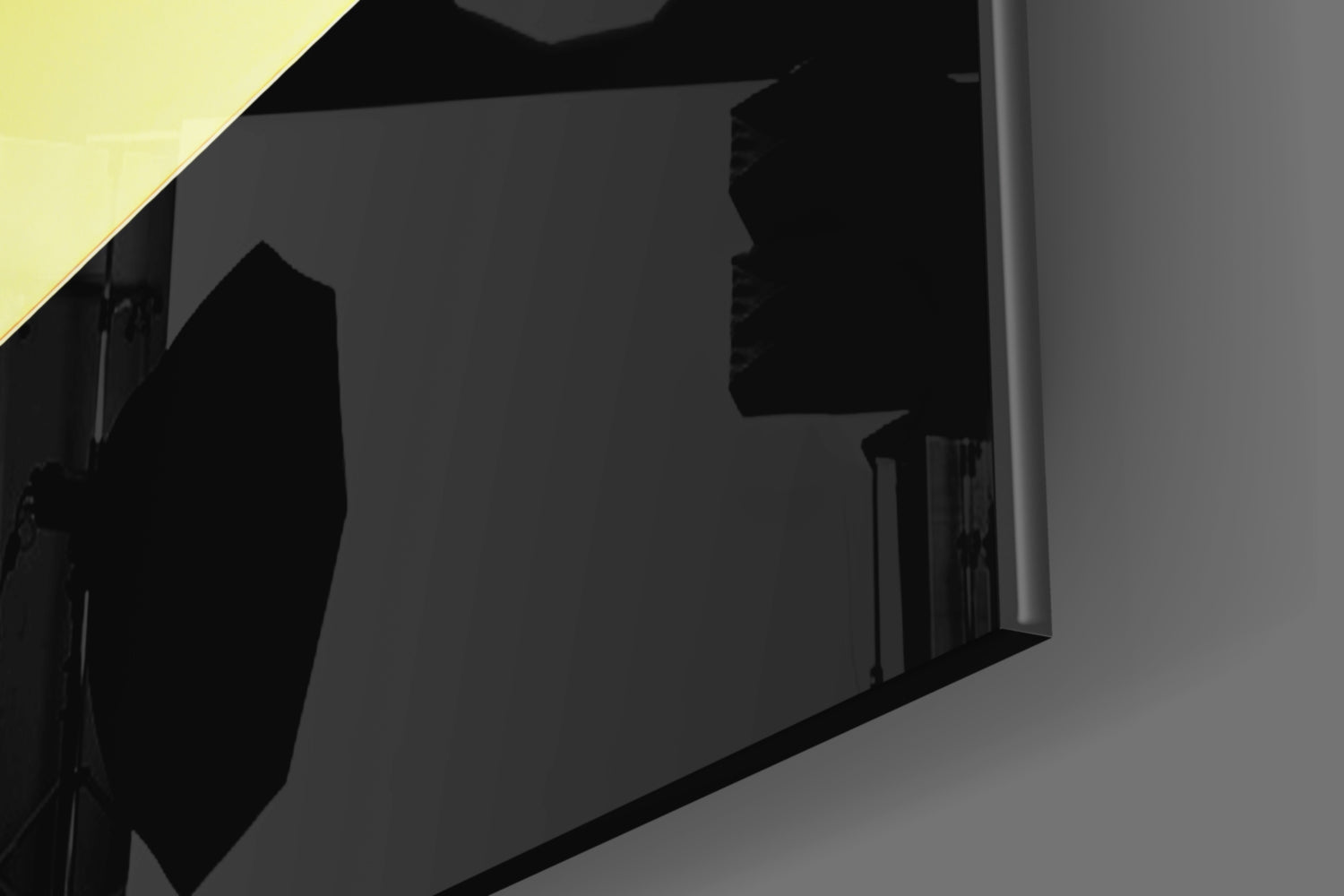 Yellow glass wall art with black silhouettes mounted on dark interior wall, angled perspective view.