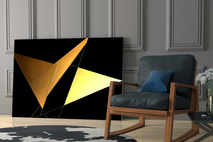 Modern living room scene featuring geometric glass wall art with golden and yellow triangular shapes on black background beside mid-century wooden chair.