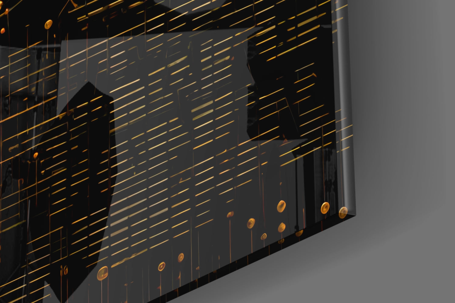 Angled view of glass wall art with gold horizontal lines, black silhouettes, and dangling gold circular elements against gray background.