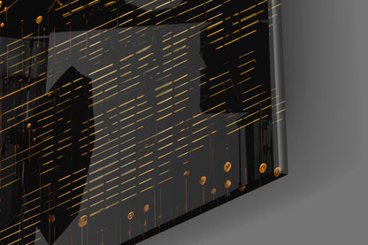 Angled view of glass wall art with gold horizontal lines, black silhouettes, and dangling gold circular elements against gray background.