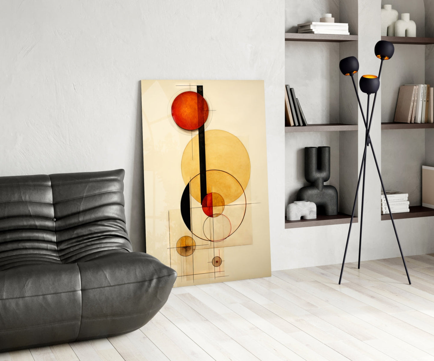Modern living room interior displaying abstract geometric glass wall art with red and yellow circles on cream background, leaning against white wall beside black leather sofa.