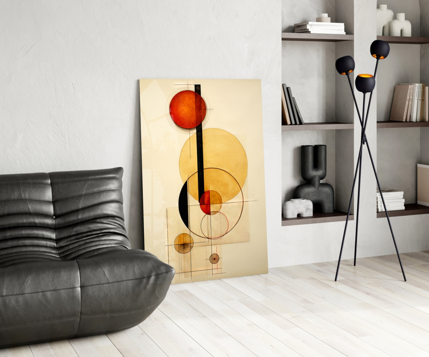 Modern living room interior displaying abstract geometric glass wall art with red and yellow circles on cream background, leaning against white wall beside black leather sofa.