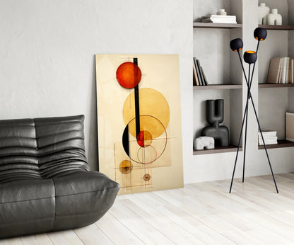 Modern living room interior displaying abstract geometric glass wall art with red and yellow circles on cream background, leaning against white wall beside black leather sofa.