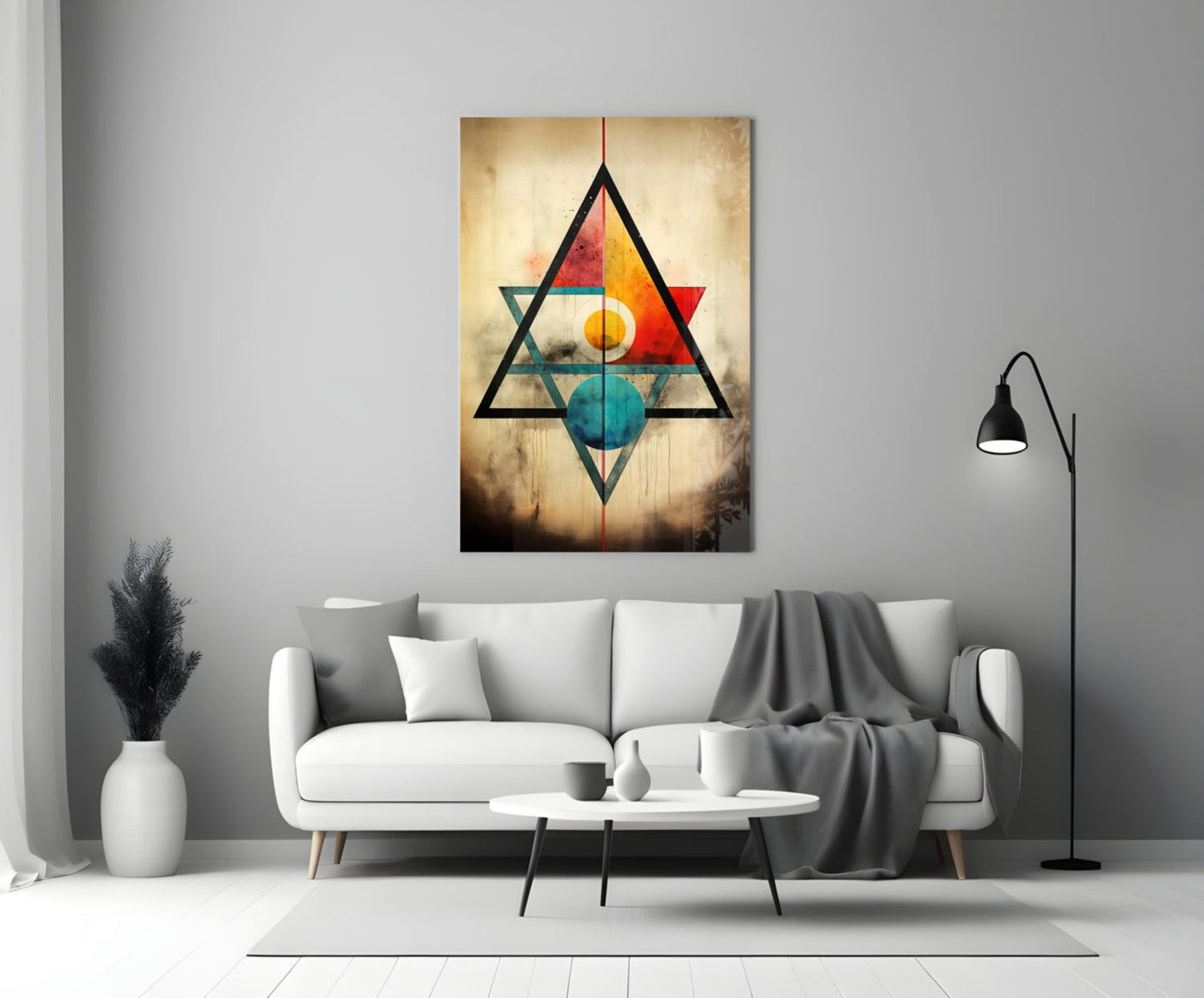 Geometric glass wall art featuring overlapping black triangles with colorful inner shapes in red, orange, yellow, teal, and blue on textured golden background, displayed above white sofa in modern living room.