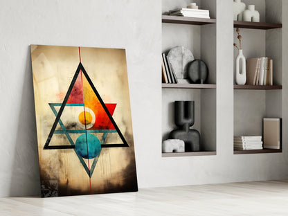 Abstract geometric glass art leaning against white wall with colorful triangles and circles in black, red, yellow, and teal.