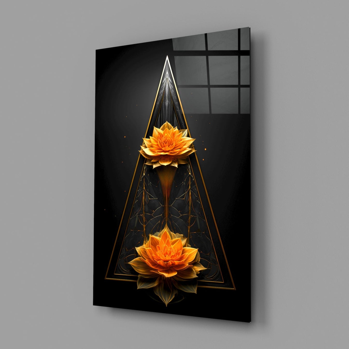 Modern glass wall art displayed at an angle showing two golden lotus flowers within geometric triangular frames on black background.