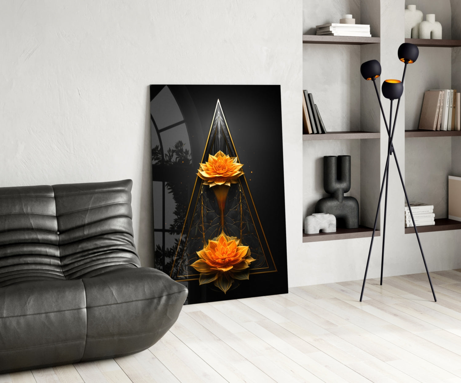 Modern living room displaying vertical glass wall art featuring two golden lotus flowers within geometric triangles on black background, leaning against white wall beside gray sofa.