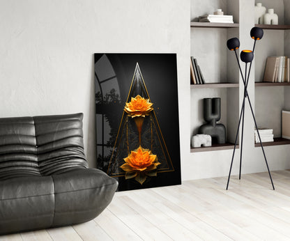Modern living room displaying vertical glass wall art featuring two golden lotus flowers within geometric triangles on black background, leaning against white wall beside gray sofa.