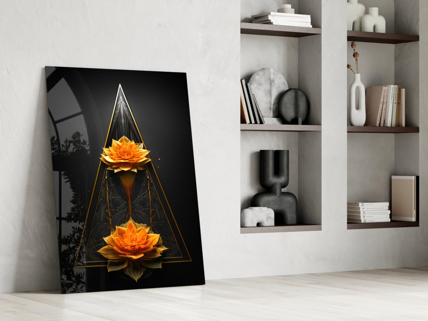 Black glass wall art leaning against white wall displays two golden lotus flowers in geometric triangular frame, styled with home décor shelving.