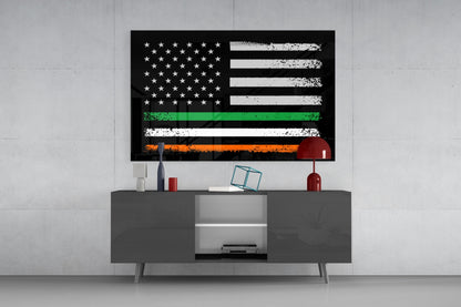 A USA-Ireland flag glass wall art piece mounted above a grey media console, displaying black background with white stars, white and black horizontal stripes, green stripe, and orange stripe.