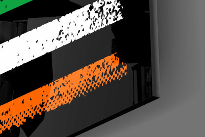 Close-up angled view of glass wall art with white and orange striped sections featuring textured black patterns on dark background.
