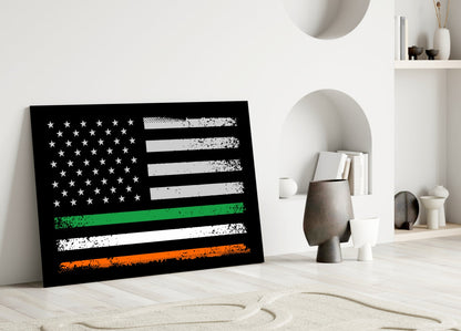 Black glass panel featuring distressed American flag with green, white, and orange horizontal stripes, displayed leaning against white wall in minimalist interior setting.
