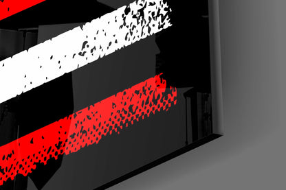 Close-up angled view of glass wall art displaying red and white diagonal stripes with black fragmented texture against gray interior wall.