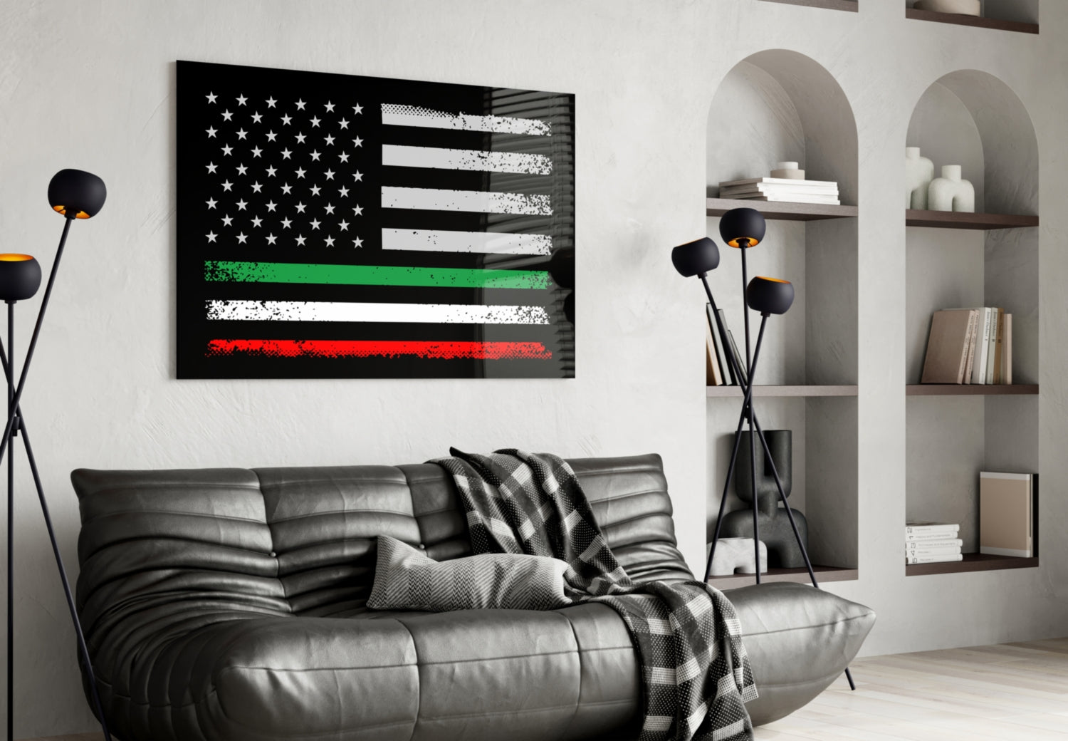 Black and white distressed American flag with green and red horizontal stripes hanging above gray leather sofa in modern living room.