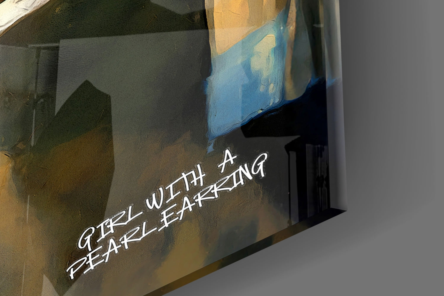 Close-up of glass wall art showing blue and gold painted figure with white text reading "GIRL WITH A PEARL EARRING" against dark background.