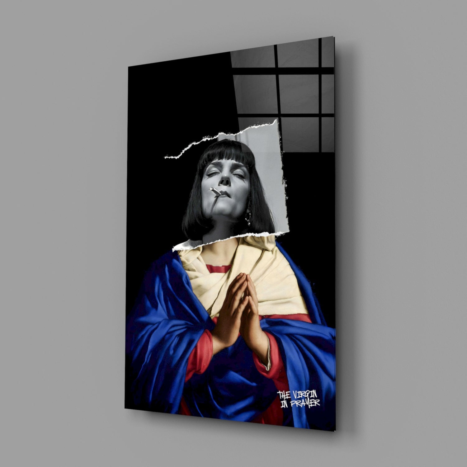 Angled product view of glass wall art featuring black and white portrait with blue and red robes, cigarette, text "THE VIRGIN IN DREAMER" visible.