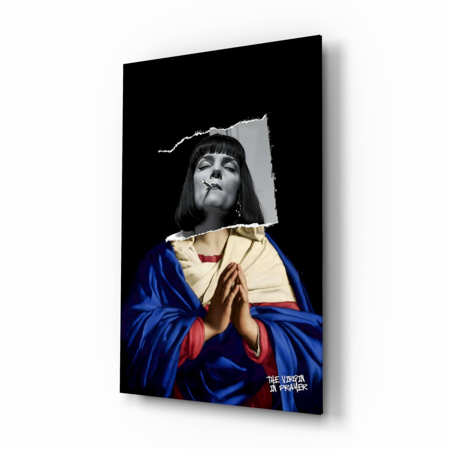 Angled product view of glass wall art featuring a black and white portrait head with colorful religious robes and "THE VIRGIN IN PRAYER" text.