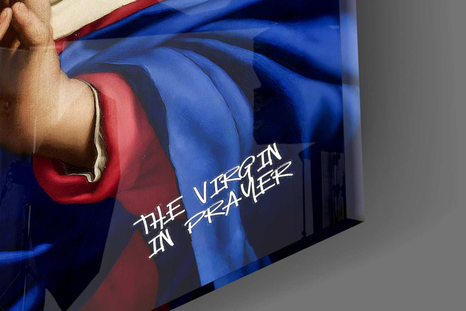 Hand holding blue and red glass wall art with "The Virgin in Pretzauer" text visible against gray background.