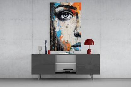 Modern living room display featuring half-portrait glass wall art with eye and colorful abstract elements above dark gray media console.