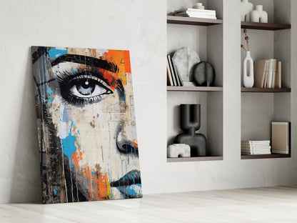 Abstract street art portrait with blue and orange paint splatters leaning against white wall beside shelving.