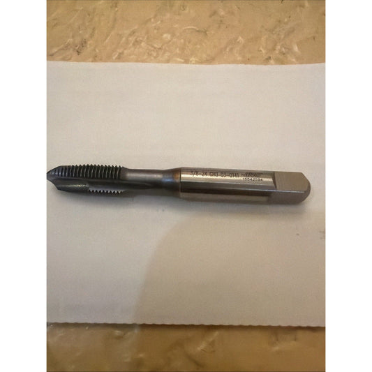 Spiral flute tap with black finish and bronze-colored shank lying horizontally on white paper, showing etched specifications on the metal band.