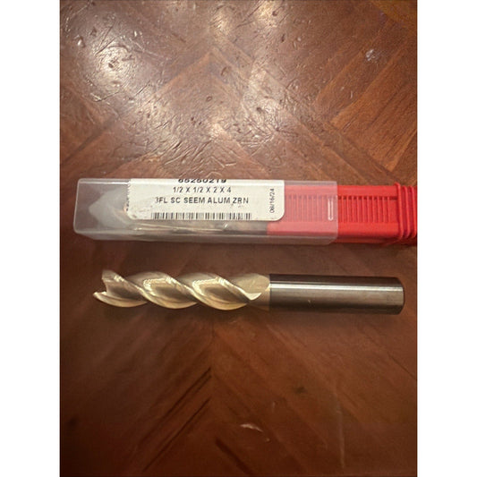 Carbide end mill with red packaging and white label displaying specifications, shown next to its clear plastic case on wooden surface.
