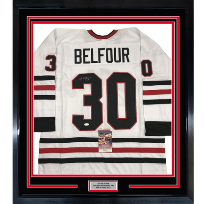 Framed white Chicago Blackhawks jersey number 30 with "BELFOUR" nameplate, red and black stripes, displayed against red and black matting with JSA authentication certificate visible.