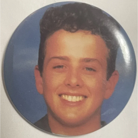 Circular portrait of a smiling young person with curly dark hair on a blue background for Electrifying Joey Close Vintage 1980s New Kids on the Block Pin, celebrating an iconic