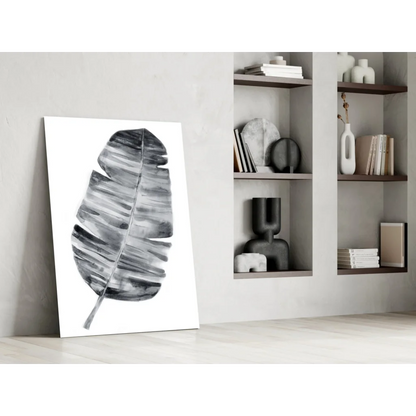 Minimalist black and white banana leaf canvas wall art leaning against wall