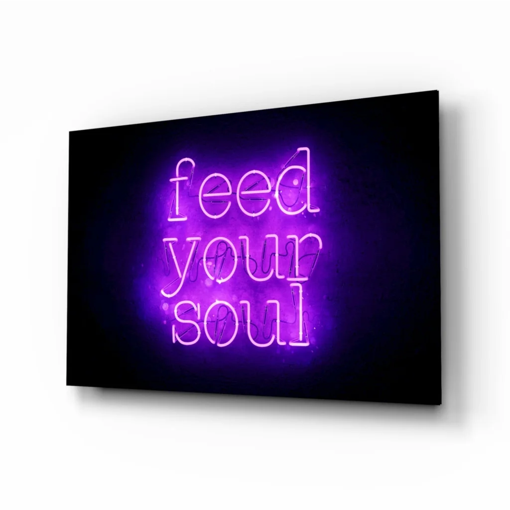 Glowing purple neon Feed Your Soul glass wall art sign on black background