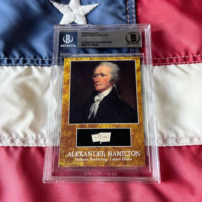 A golden-framed beckett graded alexander hamilton words trading card with authentic hamilton handwriting in a clear slab