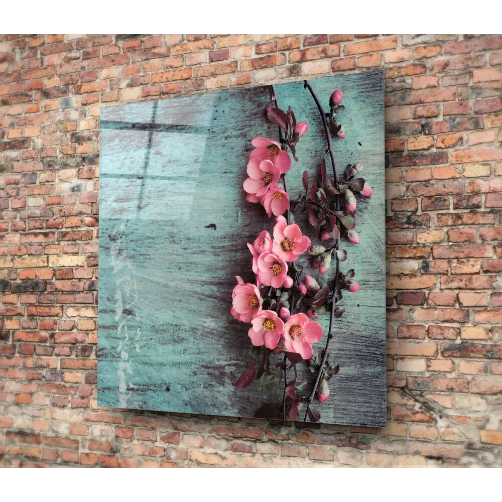 Vibrant pink blossoms on glass wall art with teal background on brick wall