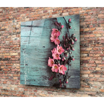 Vibrant pink blossoms on glass wall art with teal background on brick wall