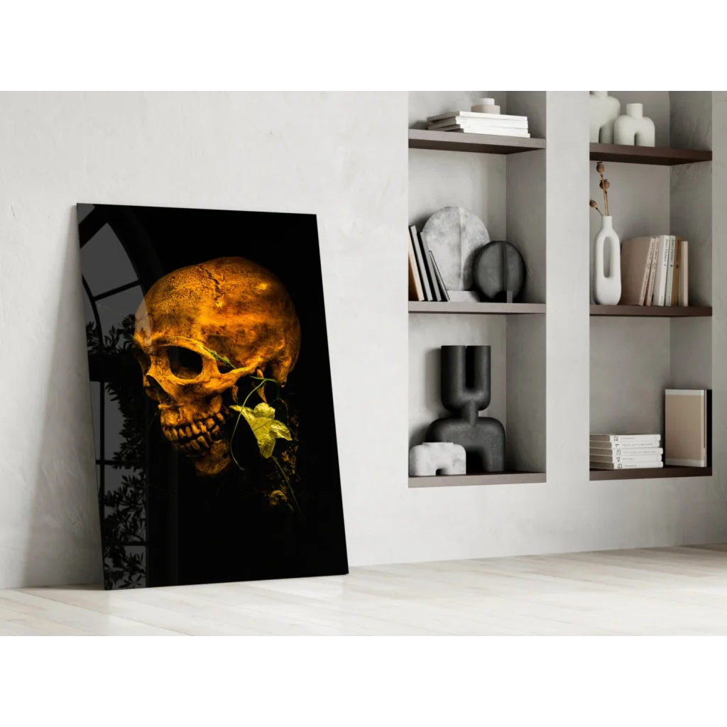 Golden skull glass wall art with leafy botanical accents leaning on white wall