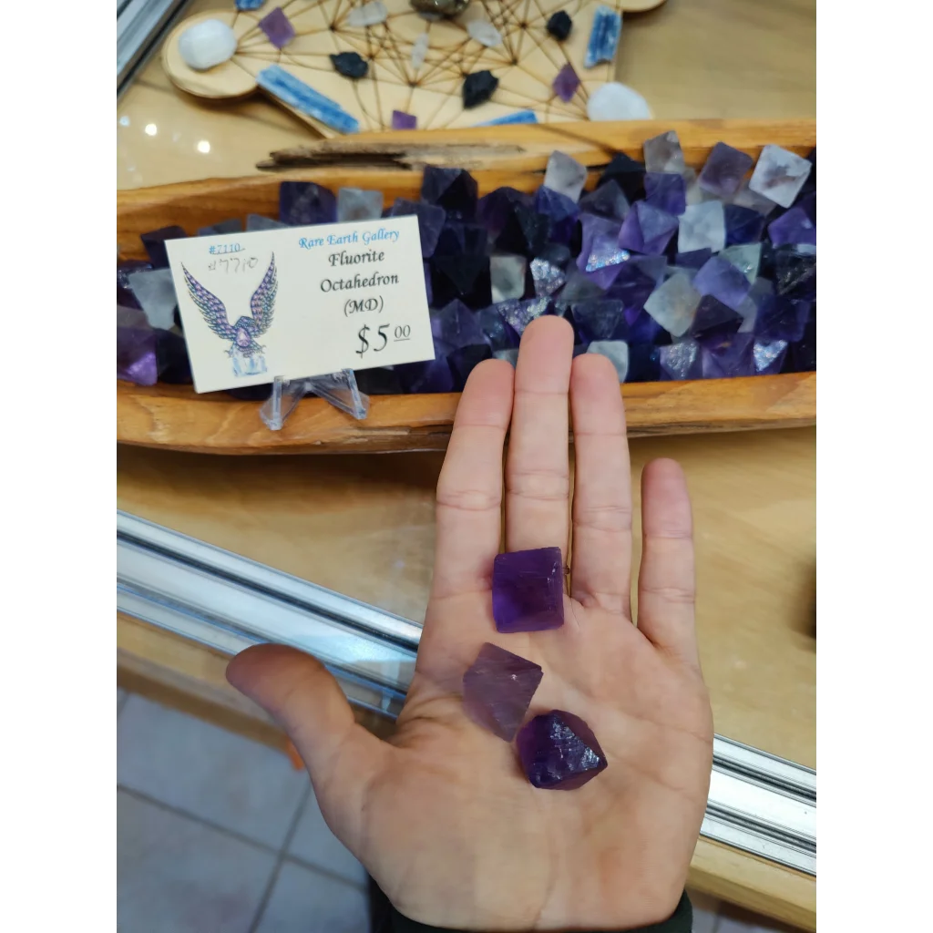 Fluorite Octahedron MD: hand holding three purple octahedrons
