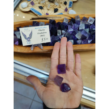 Fluorite Octahedron MD: hand holding three purple octahedrons