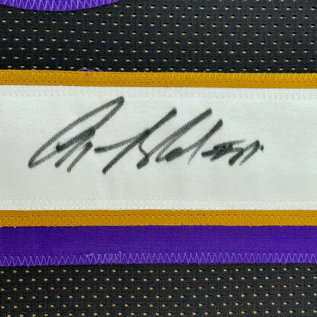 Black ink signature on white label with gold and purple trim on black mesh in framed autographed anquan boldin jersey