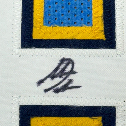 Blue and yellow embroidered patch with black border stitched on white fabric in framed signed Antonio Gates football jersey